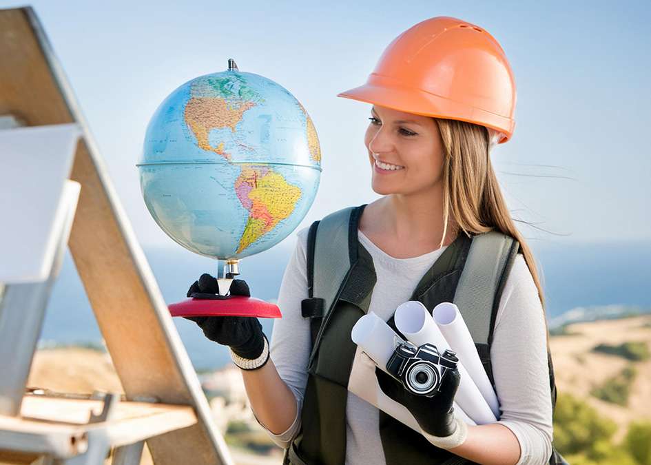 A women in a construction hat with a camera looking at a glob.